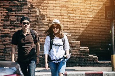 Portrait of couple walking on road against wall
