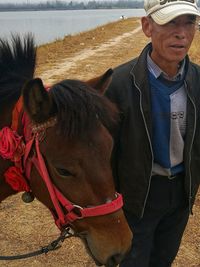 Young man with horse standing at beach