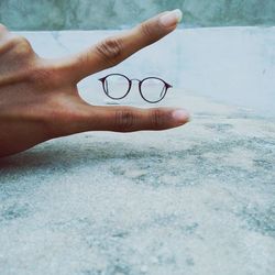 Cropped hand showing peace sign by eyeglasses