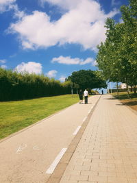 Rear view of people walking on footpath in city