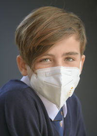 Close-up portrait of boy wearing flu mask against gray background