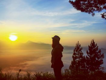 Silhouette man standing by tree against sky during sunset