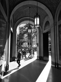 People walking in colonnade during sunny day