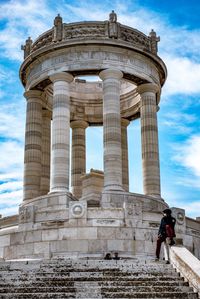 Man sitting at historical building against 
sky