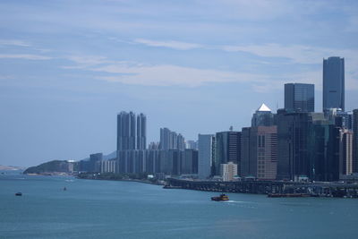 Sea and buildings in city against sky