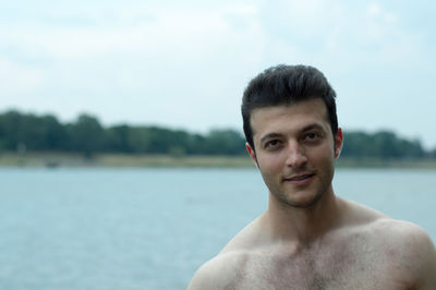 Portrait of shirtless young man against sky