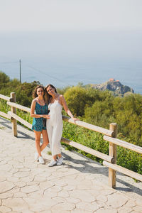 Woman smiling while standing on railing against mountain