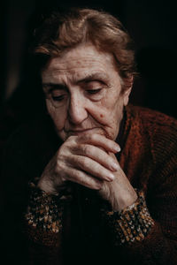 Close-up of sad senior woman against black background