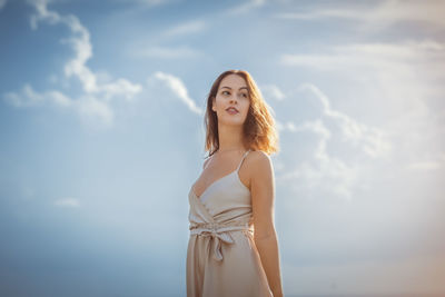 Portrait of young woman standing against sky