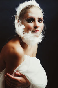 Close-up portrait of young woman against black background