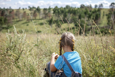 Rear view of girl sitting on field