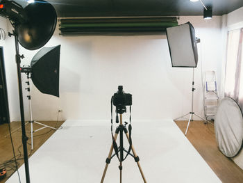 Tripod camera and lighting equipment in empty studio