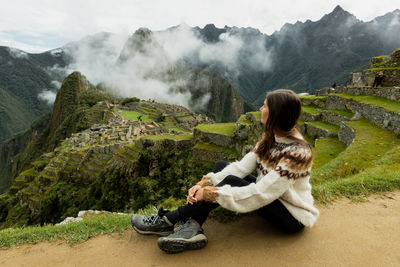 Side view of woman sitting on mountain