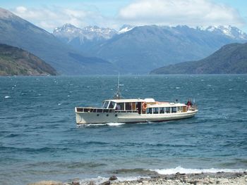 Boat sailing in sea against mountains