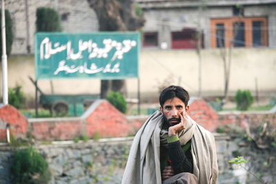 Portrait of man standing against sign in city