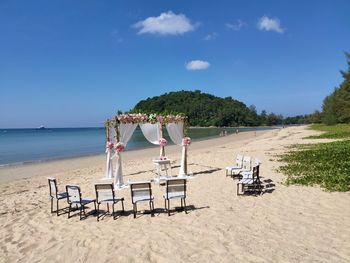 Chairs on beach against sky
