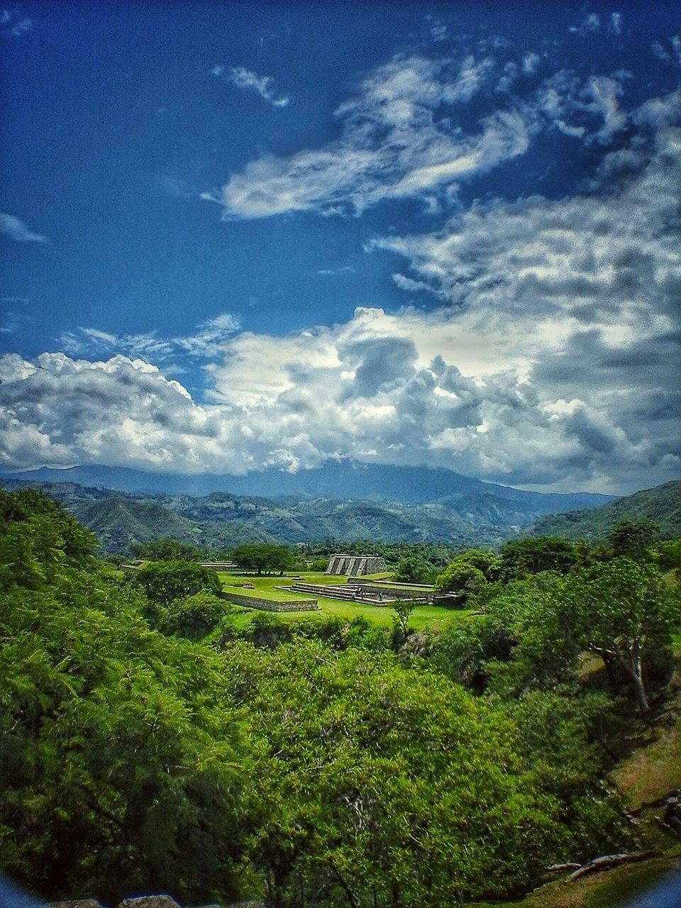 sky, tranquil scene, tranquility, scenics, beauty in nature, landscape, green color, nature, cloud - sky, growth, grass, cloud, tree, mountain, blue, non-urban scene, plant, idyllic, day, green, outdoors, remote, no people, cloudy, lush foliage, non urban scene, hill, horizon over land, grassy