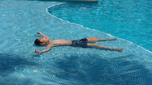 High angle view of boy relaxing in swimming pool