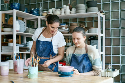 Women working on table in pottery shop