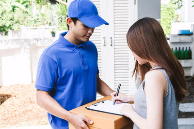 Woman signing on paper while salesman holding cardboard box