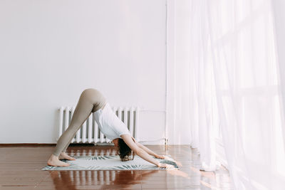 Side view of woman sitting on wooden floor