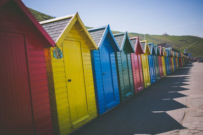 Multi colored huts on beach by building against sky