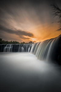 Scenic view of waterfall against sky during sunset