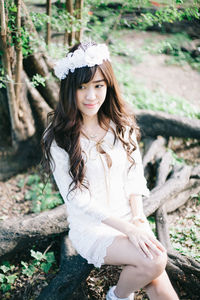 Beautiful young woman sitting on tree roots