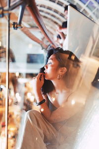Woman looking away while sitting on window