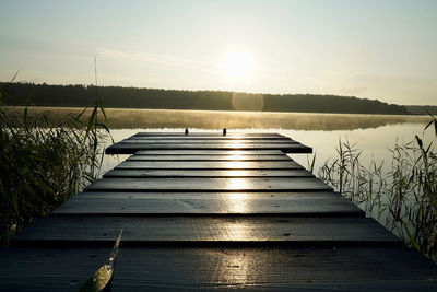 Pier over lake against sky during sunset