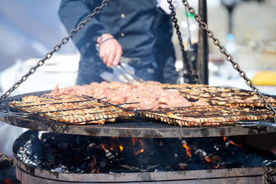 Midsection of man preparing food on barbecue grill