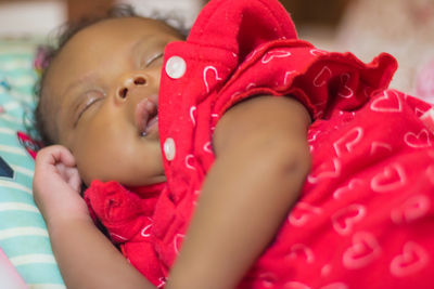 Close-up of baby girl lying on bed