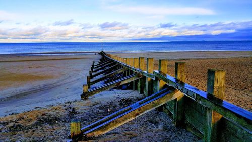 Pier on beach against sky