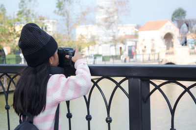 Rear view of girl photographing railing