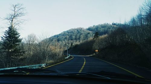 Road amidst trees against clear sky