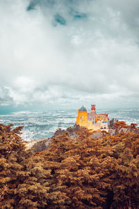 Castle on mountain against cloudy sky