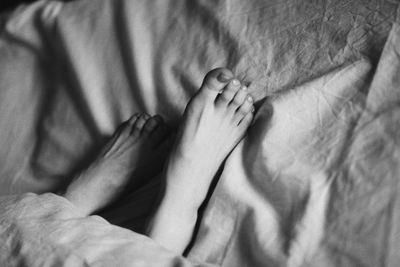 Low section of woman relaxing on bed at home