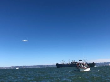 Sailboat in sea against clear blue sky