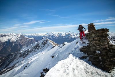 Man standing on snowcapped mountain against sky