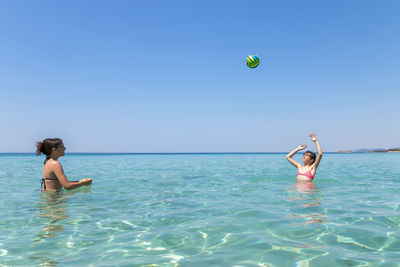 Happy teenagers playing volleyball in water at the vacation and fun