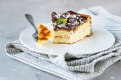 A piece of homemade no crust cheesecake with chocolate sauce topping, coconut flakes and mint. 
