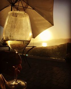 Close-up of wine in glass against sky at sunset