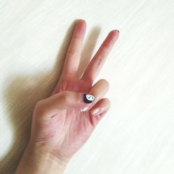 Close-up of hand with nail art gesturing peace sign on table