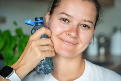 Portrait of young woman holding bottle