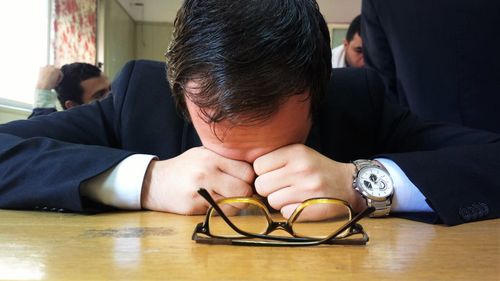 Tired businessman resting on table at cafe