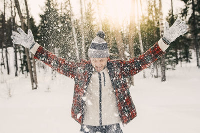 Happy mid adult man playing with snow on snow covered field