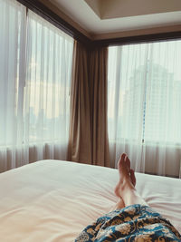 Low section of woman relaxing on bed at home