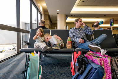 Two girls and father sitting in airport terminal waiting for plane