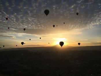 Parachutes over silhouette landscape at sunset