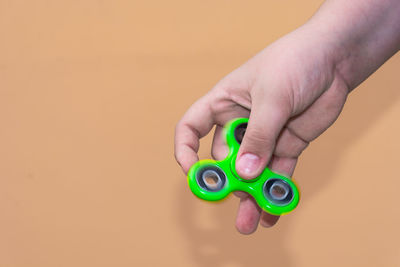 Close-up of hand holding toy against colored background